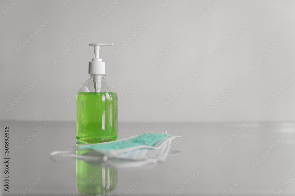 Medical mask lies on the table, next to a bottle of liquid soap on a white background. High quality photo Medical mask lies on the table, next to a bottle of liquid soap on a white background. High quality photo