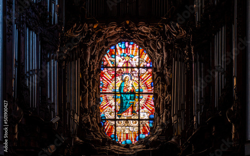 Virgin Mary in the stained glass window and an old musical organ