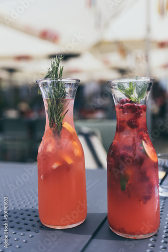 bottles with pink homemade lemonade with herbs and fruit, standing on restaurant table, 