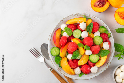 Fresh summer fruit salad made of watermelon, peach, cucumber, mozzarella cheese and mint in a plate