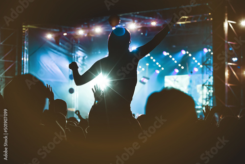 Photography Girl silhouette with raising hands and mobile phone during enjoying music concert