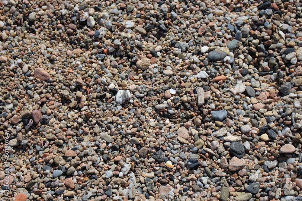 A closeup image of the ground of the beach full of pebbles in a small town in the Mediterranean Sea. Vacations, summer, holidays. A closeup image of the ground of the beach full of pebbles in a small town in the Mediterranean Sea. Vacations, summer, holidays.