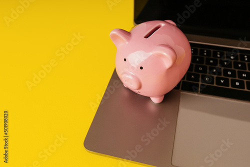 Piggy bank on a keyboard isolated on yellow background. Online banking concept