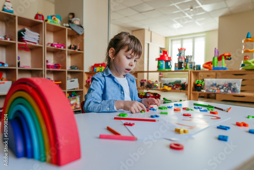 Little girl playing with letters at kindergarten