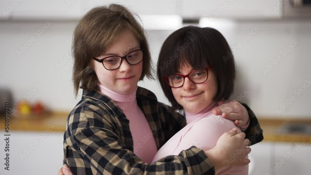 Two happy girls with down syndrome in eyeglasses standing together embracing Two happy girls with down syndrome in eyeglasses standing together embracing