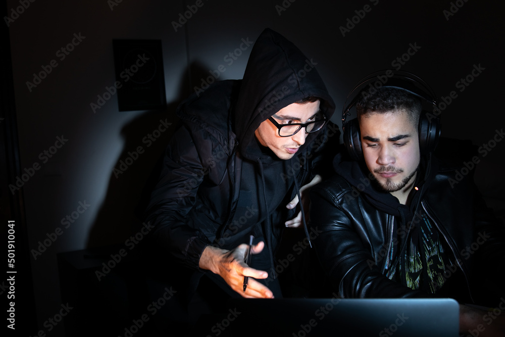 Portrait of focused hackers at work. Men in casual clothes looking at laptop screen, typing, talking. Hacking, computer concept Portrait of focused hackers at work. Men in casual clothes looking at laptop screen, typing, talking. Hacking, computer concept