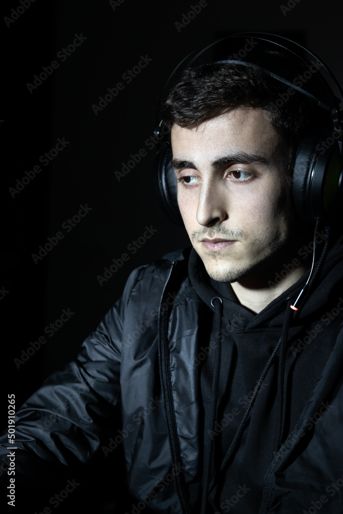 Portrait of young good-looking man in earphones. Dark-haired man in casual clothes looking at screen. Portrait concept Portrait of young good-looking man in earphones. Dark-haired man in casual clothes looking at screen. Portrait concept