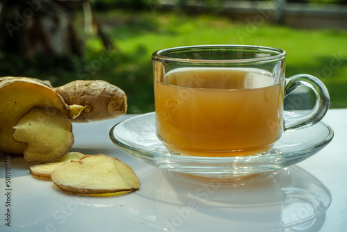 Hot ginger juice with slices of ginger on a white table under the morning sunlight, hot ginger water can help to heat up the body.