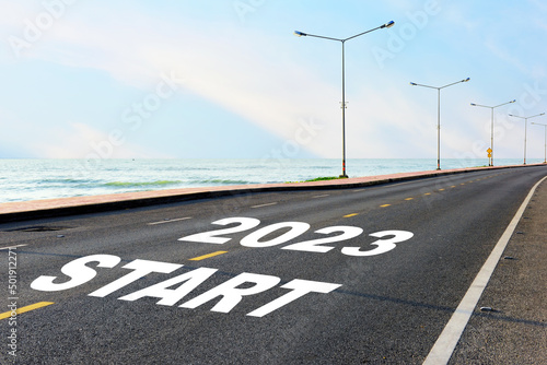 Start new year 2023 on asphalt road with marking line for given direction and sea landscape. Road to recovery concept and business success idea
