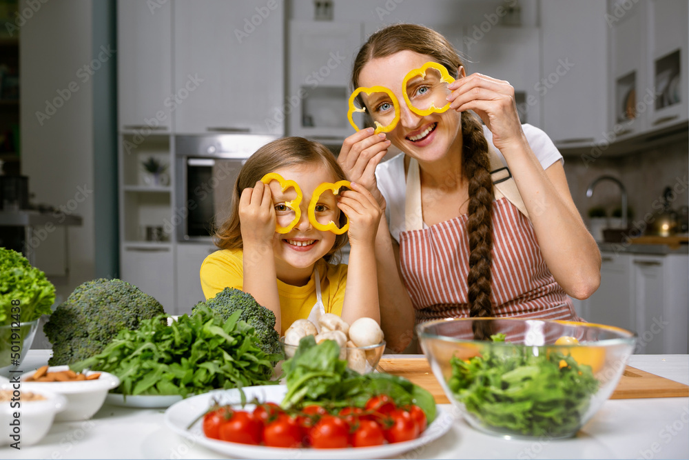 mom and her daughter playfully prepare healthy and proper nutrition from fresh vegetables and herbs mom and her daughter playfully prepare healthy and proper nutrition from fresh vegetables and herbs