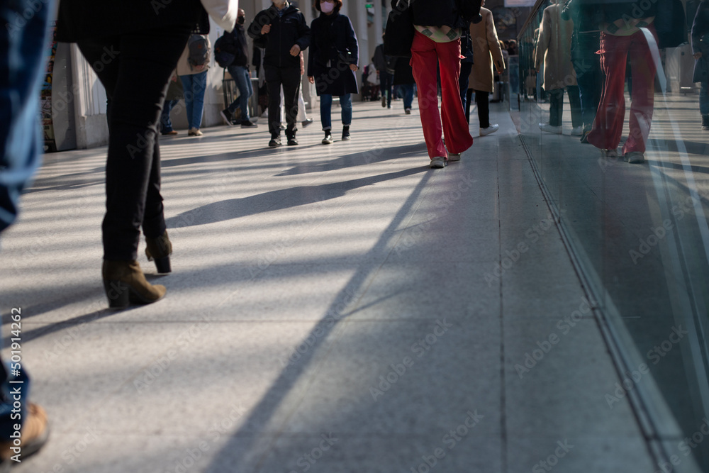 foule qui se déplace dans le même sens dans un centre commercial. On ne voit que le mouvement des jambes. 