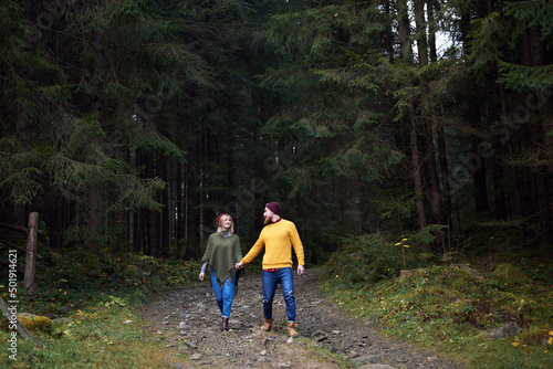 Young couple in love walking in forest together. Carpathian mountains travel in Ukraine. Two tourists spending relaxing time in the woods. Romantic relationship of young people.