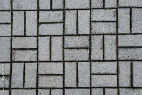 Gray paving stones after rain as background. Road surface in urban environment. Transport infrastructure. Brick wall as abstraction