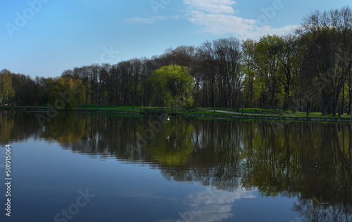 Beautiful landscape of the shore of the pond lake with the reflection of the blue sky in the water ...
