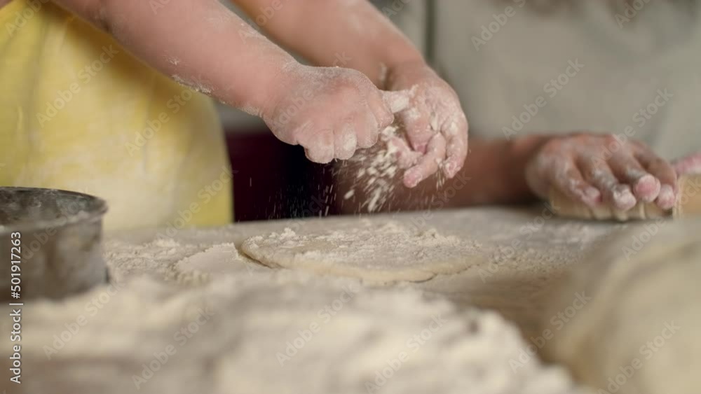 Child's hands sprinkle flour on the dough while baking.Dough Cooking,Child Education,Home Food,Sweet Pastries. Child's hands sprinkle flour on the dough while baking.Dough Cooking,Child Education,Home Food,Sweet Pastries.