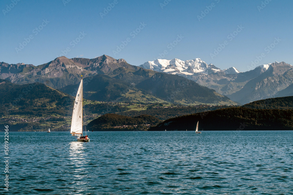 A lake in Switzerland surrounded by high mountains. Boats and sailboats sail across the lake.