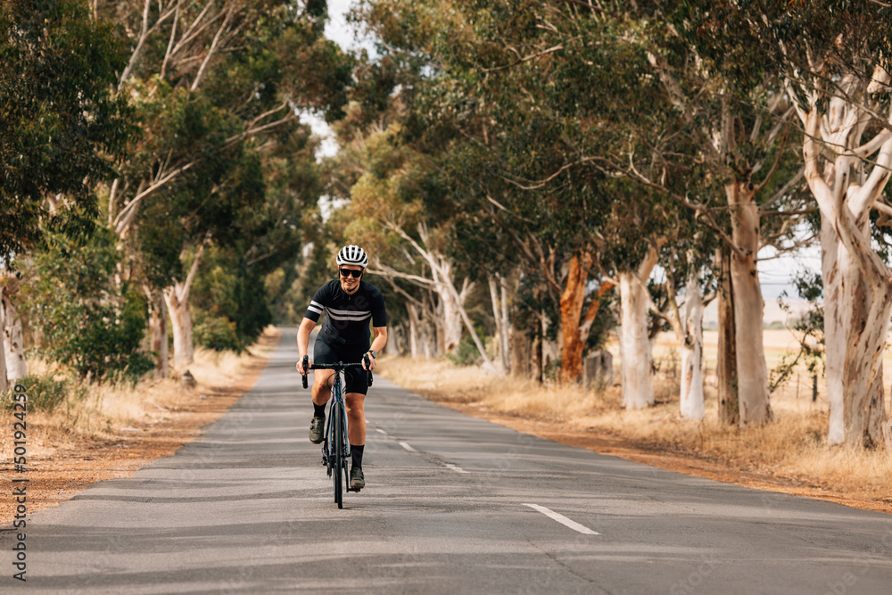 Smiling woman in sportswear riding her bike on empty countryside road