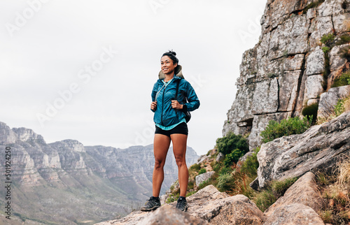 Young female hiker with backpack standing on mountain enjoying the view photo