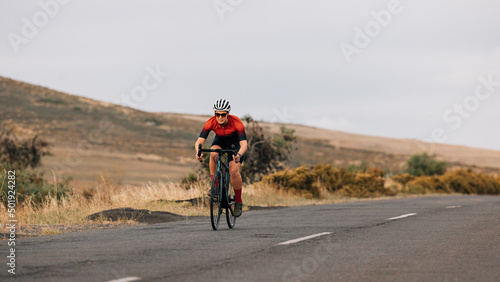 Professional woman cyclist in sportswear practicing on a empty road