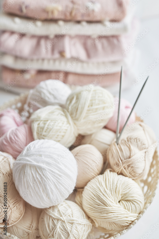 Stack of knitted clothes and balls of yarn, knitting needles, accessories for knitting. Baby clothes. Needlework, hobby, knitting, handwork. Stack of knitted clothes and balls of yarn, knitting needles, accessories for knitting. Baby clothes. Needlework, hobby, knitting, handwork.