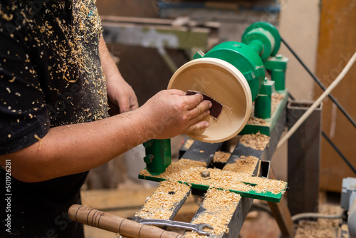 Fototapeta Naklejka Na Ścianę i Meble -  Closeup of person sanding wooden product using sandpaper on a lathe