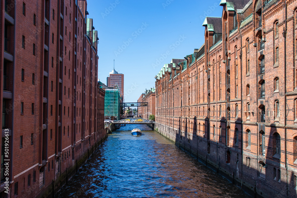  View of famous Speicherstadt warehouse district. Old brick building, river canal of Hafencity quarter. Hamburg skyline.