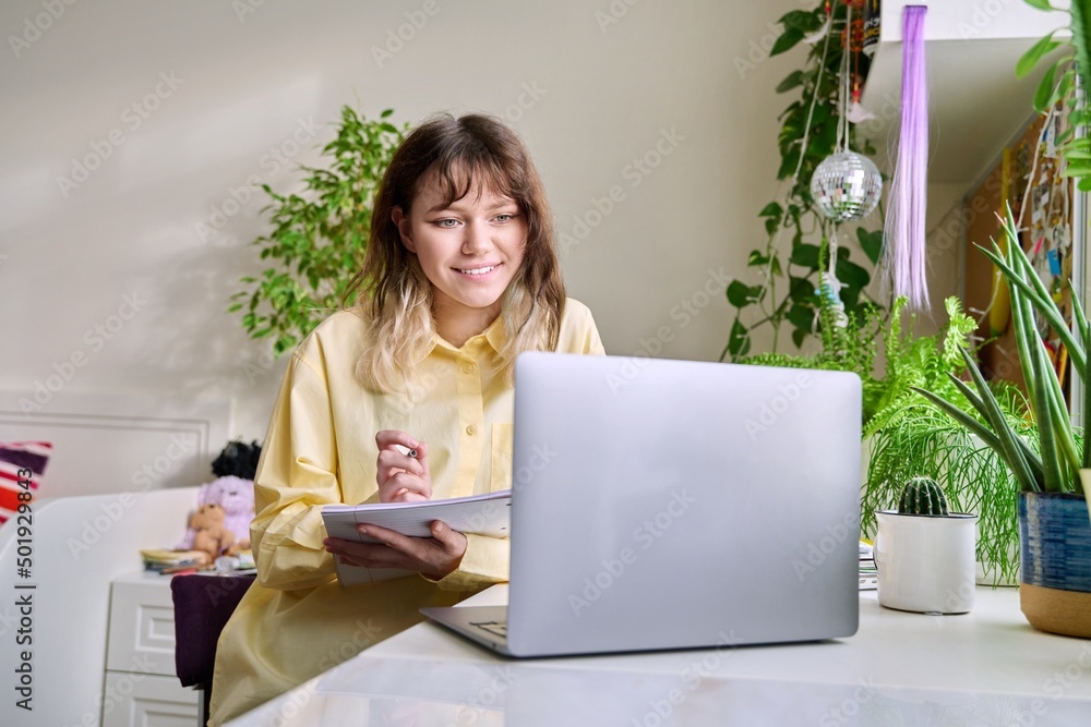 Teenage female student studying at home using a laptop Teenage female student studying at home using a laptop