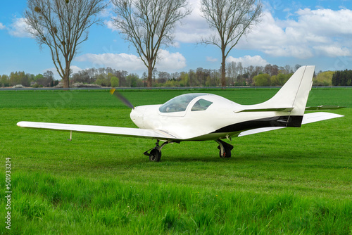 A bright white plane ready to take off at a grassy airport.