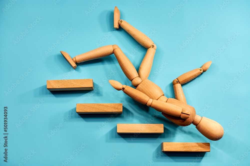 wooden figure man falling down from stairs