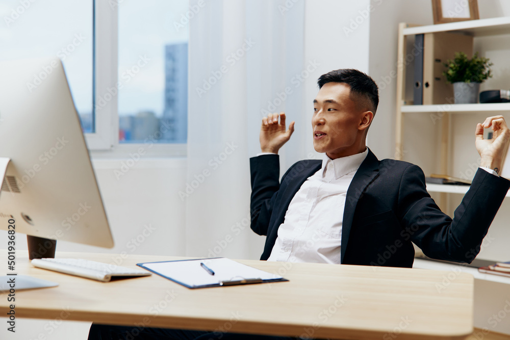 Asian man sitting at a desk in front of a computer technologies Asian man sitting at a desk in front of a computer technologies