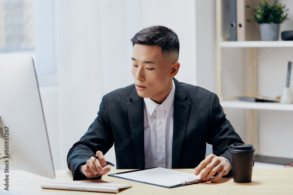 manager in a suit glass of coffee sits at a tablein front of a computer technologies