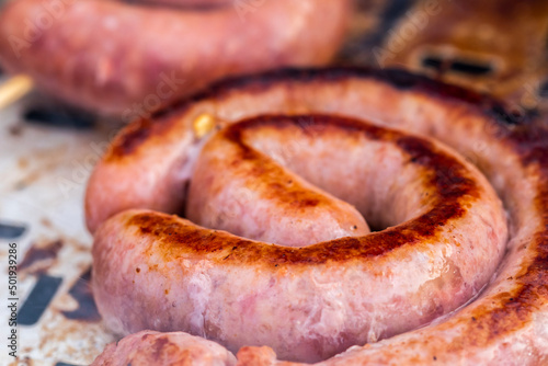 Close up shot of rolled up sausages on skewer placed over barbeque