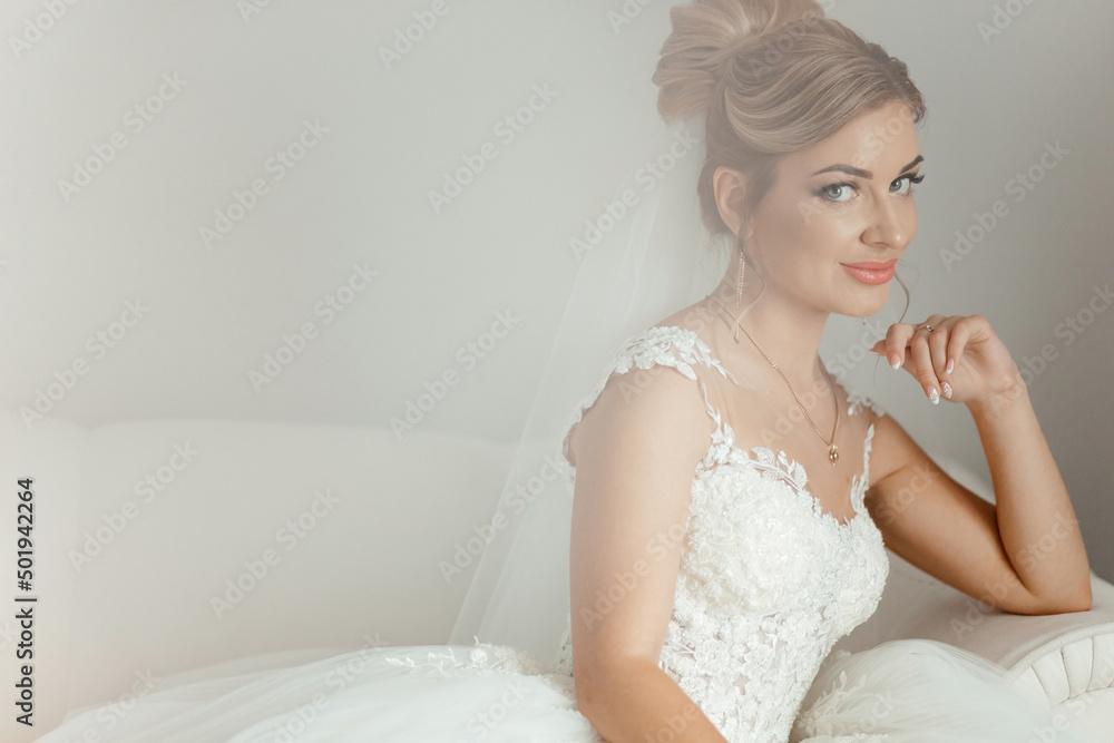Beautiful bride sitting on a white sofa and looking at the camera Beautiful bride sitting on a white sofa and looking at the camera