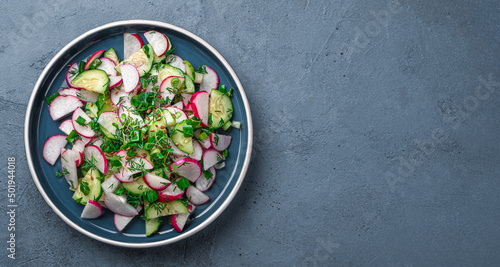 Salad with radishes, cucumber, micro greens and flax seeds on a dark background. Top view, copy space.