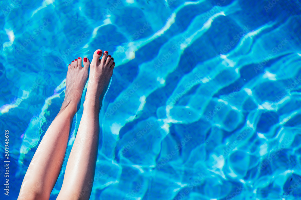 view from above of woman legs over blue pool water, copy space