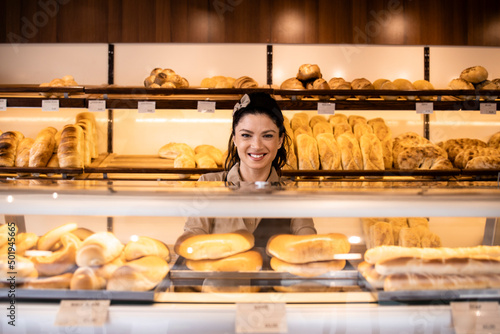 Bakery shop interior and female worker selling fresh tasty pastry and bread.