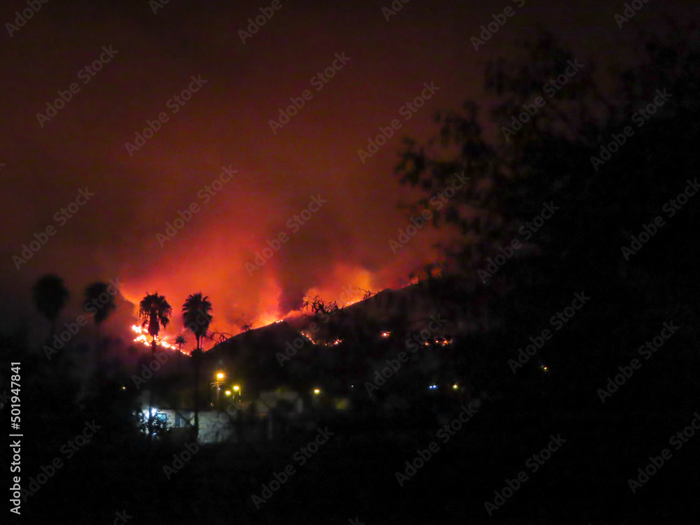A Mountain Wildfire in San Bernardino, California, with the night sky Shining Orange withSmoke from the Fire A Mountain Wildfire in San Bernardino, California, with the night sky Shining Orange withSmoke from the Fire
