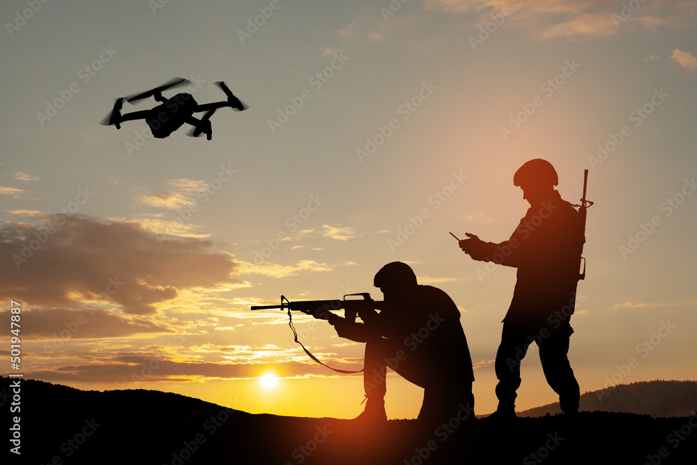 Silhouettes of soldiers are using drone and laptop computer for scouting during military operation against the backdrop of a sunset. Greeting card for Veterans Day, Memorial Day, Independence Day. Silhouettes of soldiers are using drone and laptop computer for scouting during military operation against the backdrop of a sunset. Greeting card for Veterans Day, Memorial Day, Independence Day.