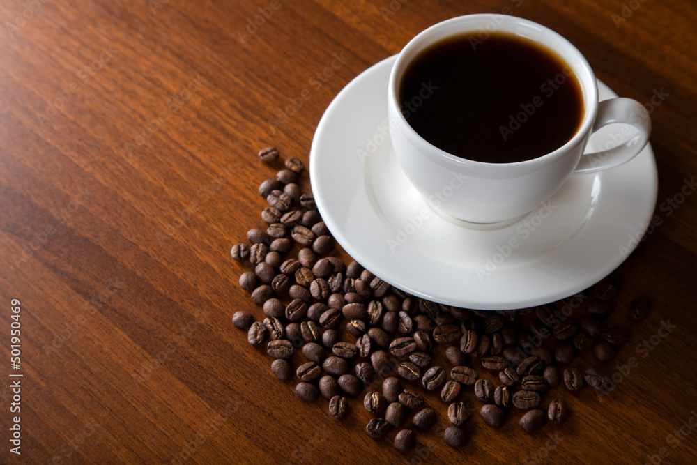 Obraz premium Coffee beans with a cup of coffee on wooden background