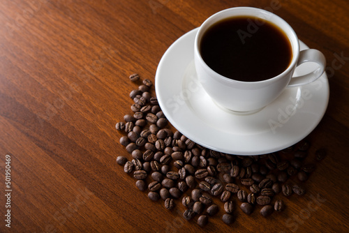 Coffee beans with a cup of coffee on wooden background 