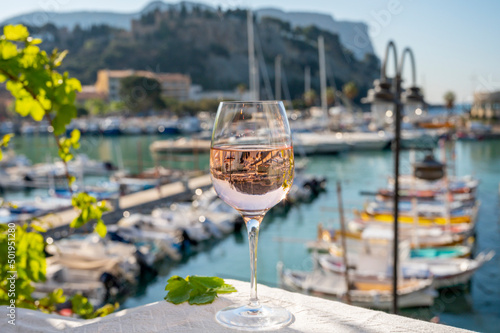 Rose wine in glass served on outdoor terrace with view on old fisherman's harbour with colourful boats in Cassis, Provence, France photo