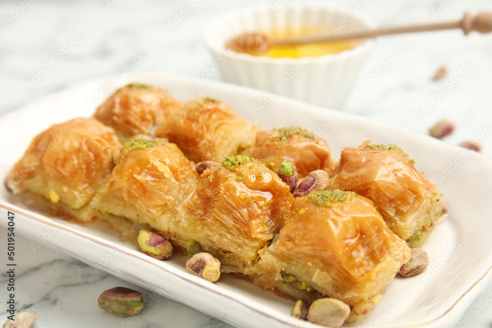 Delicious baklava with pistachios and scattered nuts on white marble table, closeup Delicious baklava with pistachios and scattered nuts on white marble table, closeup