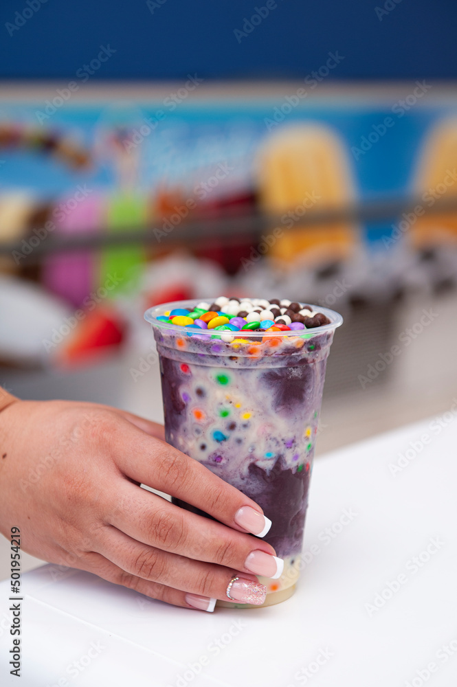 Woman's hand holding a plastic cup of frozen açaí. Copy space. Woman's hand holding a plastic cup of frozen açaí. Copy space.