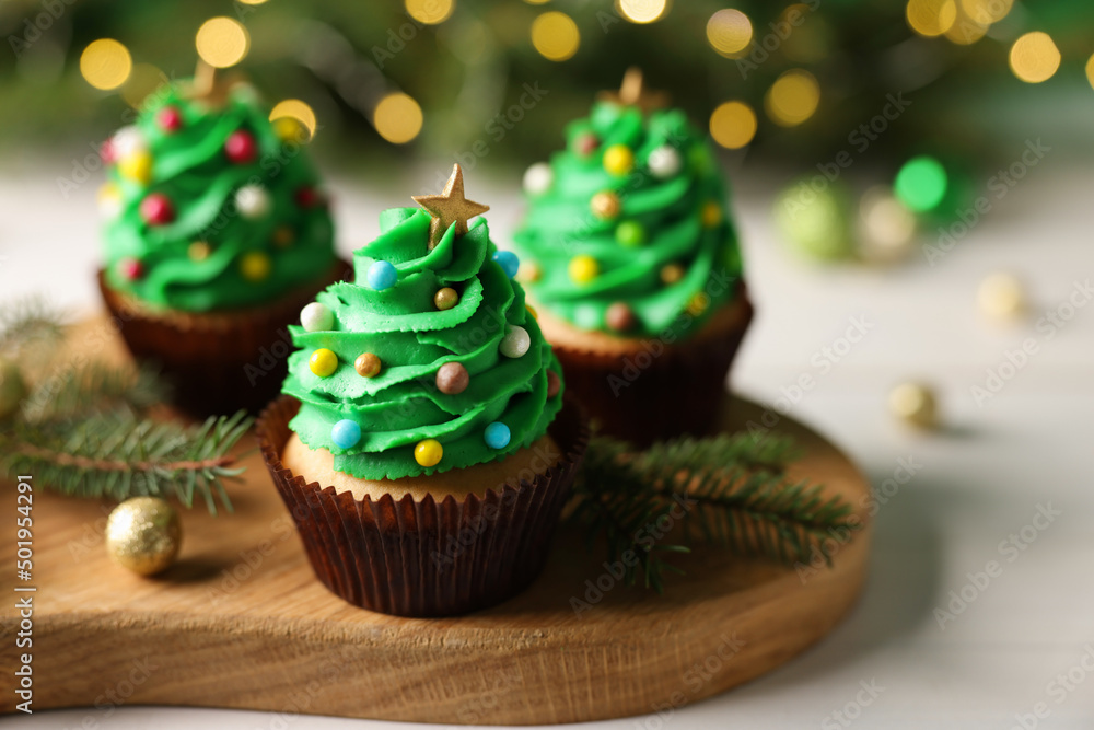 Tasty Christmas cupcakes on wooden board, closeup. Space for text