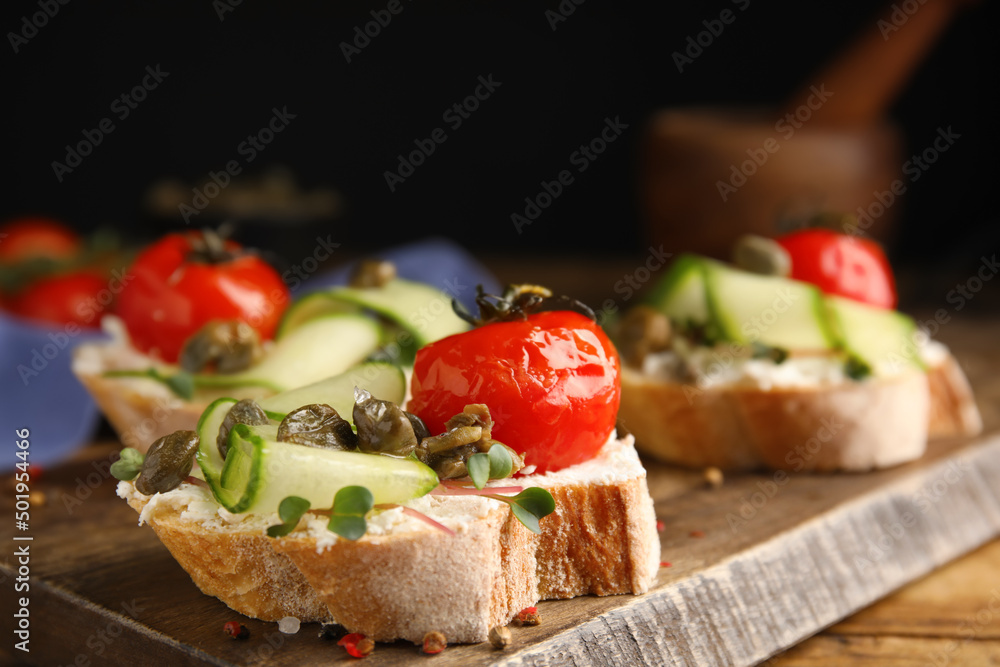 Bruschettas with capers, vegetables and cream cheese served on wooden board, closeup Bruschettas with capers, vegetables and cream cheese served on wooden board, closeup