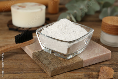 Tooth powder and brush on wooden table, closeup