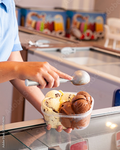 Woman's hand putting creamy ice cream into the jar to take home. Space for text. photo