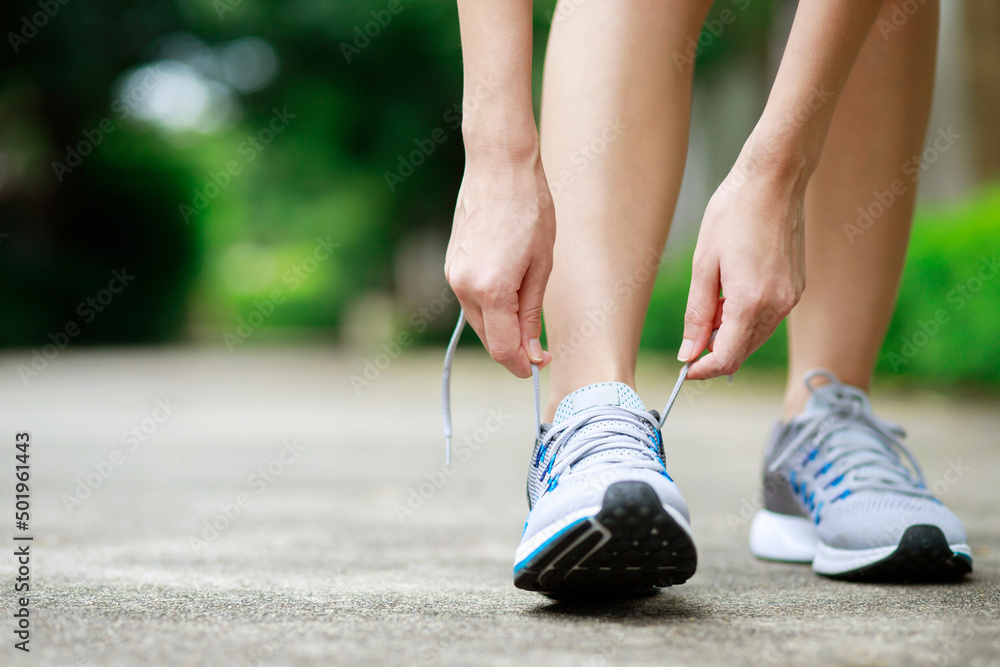 Running shoes. close up female athlete tying laces for jogging on road. Runner ties getting ready for training. Sport lifestyle. copy space banner. Running shoes. close up female athlete tying laces for jogging on road. Runner ties getting ready for training. Sport lifestyle. copy space banner.