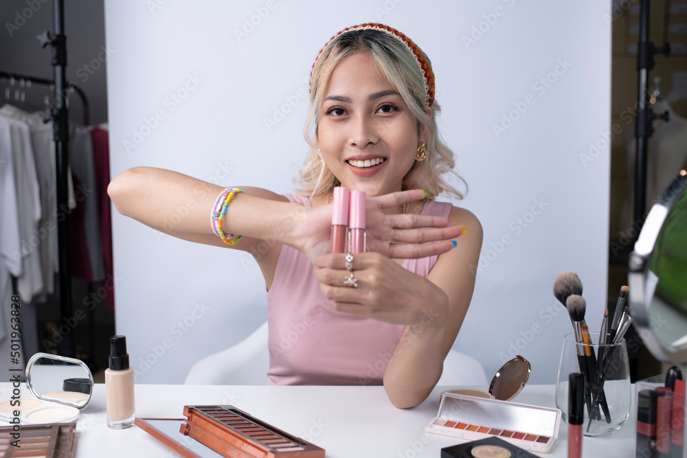 Naklejka premium Young beautiful Asian woman and professional beauty make up artist vlogger or blogger recording makeup tutorial to share on website or social media. Business online influencer on social media concept.