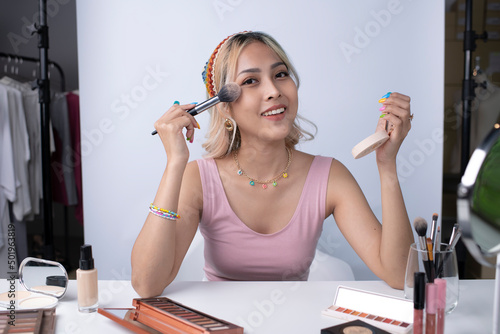 Fotografi Young beautiful Asian woman and professional beauty make up artist vlogger or blogger recording makeup tutorial to share on website or social media